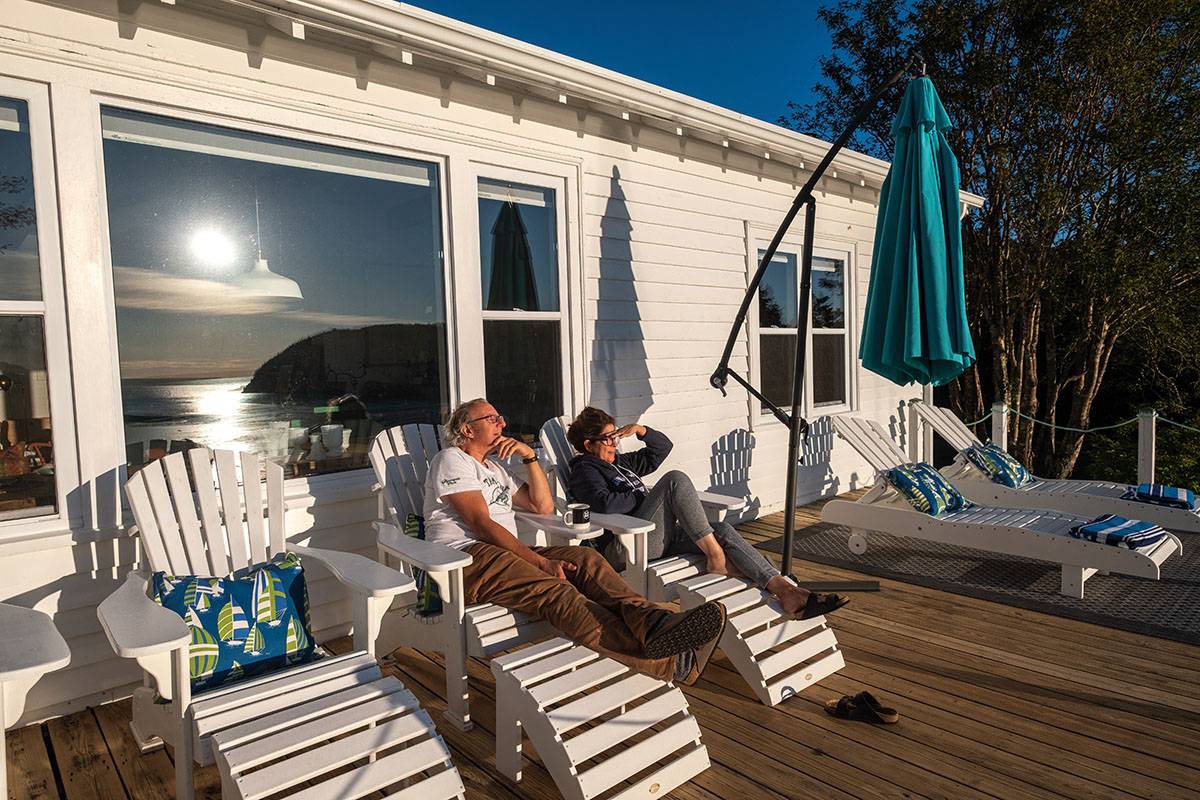 Pauline and Robbie sitting on Muskoka lounge chairs on their cottage deck