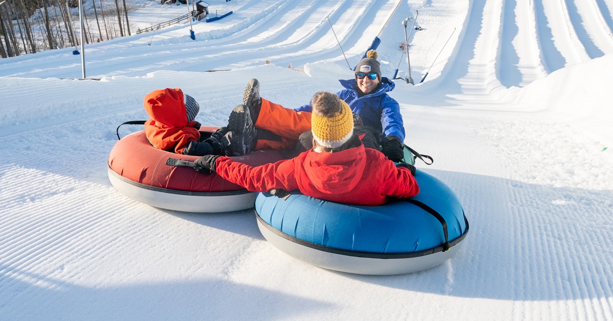 People holding hands on snow tubes