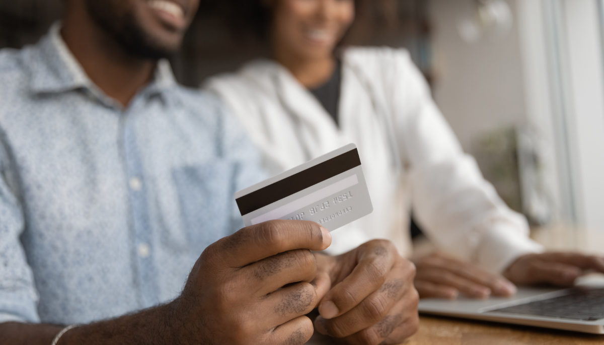 Couple using a credit card to book something and pay a fee on a laptop