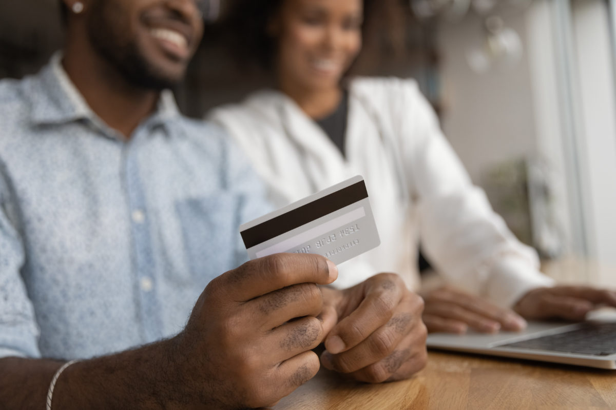 Couple using a credit card to book something and pay a fee on a laptop