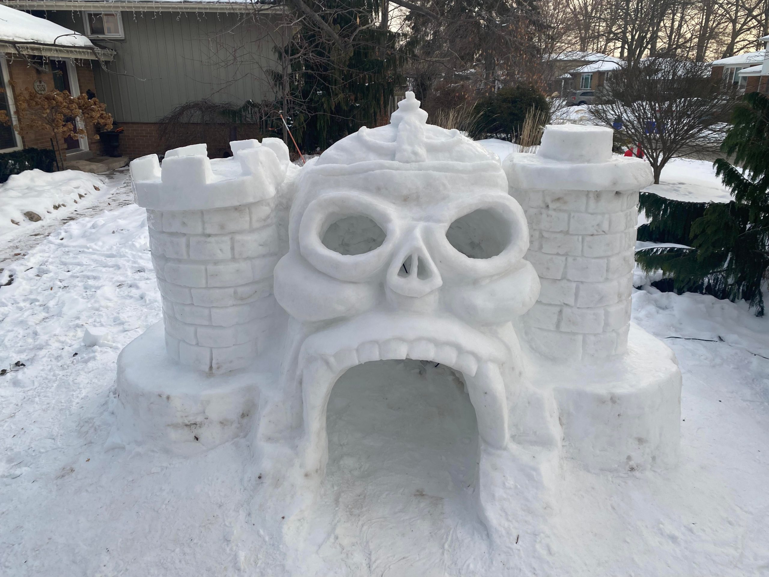 An igloo shaped like a castle with the entrance in the shape of a skull.