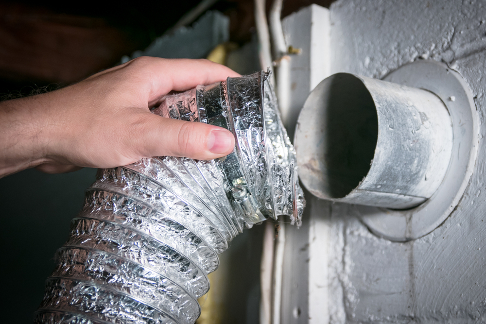 A hand removing the aluminum dryer vent hose