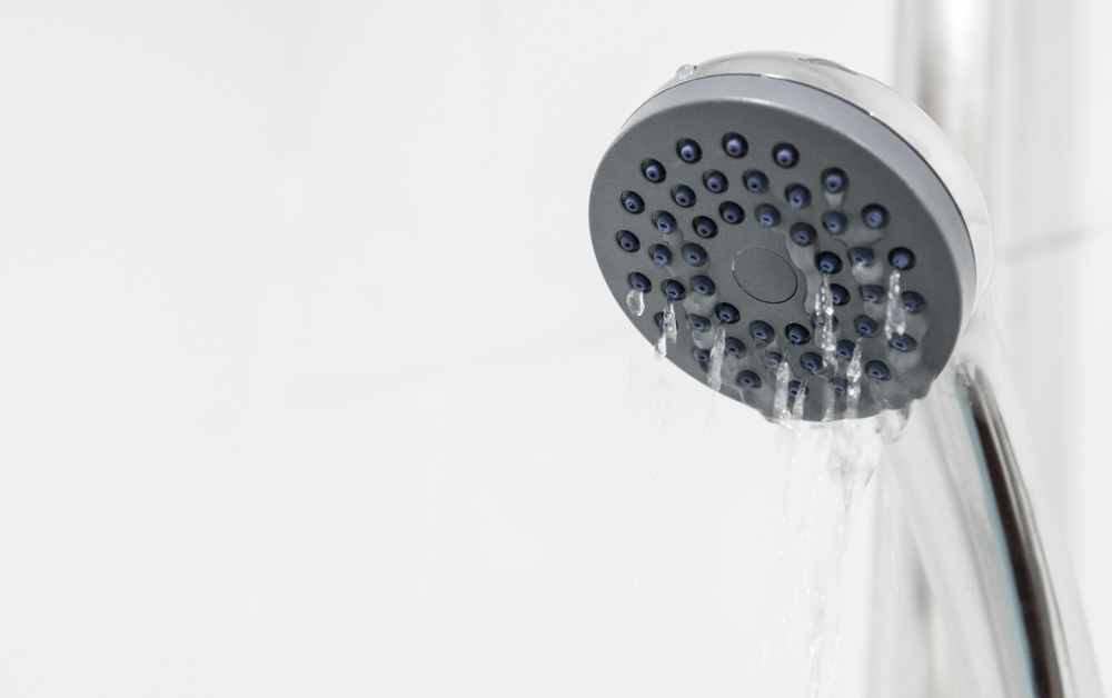 Close-up of a silver shower head with water coming out of it