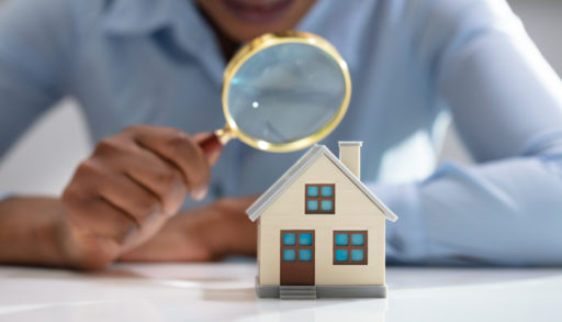 Close up of a woman's hand holding a magnifying glass over a model home
