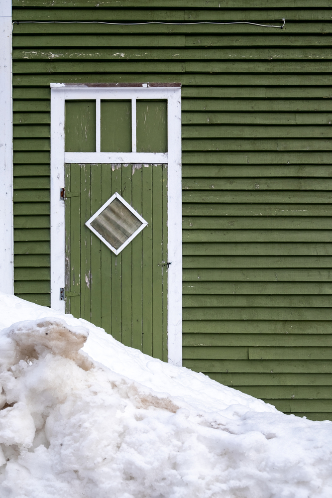 The exterior door of a building with snow in front of it