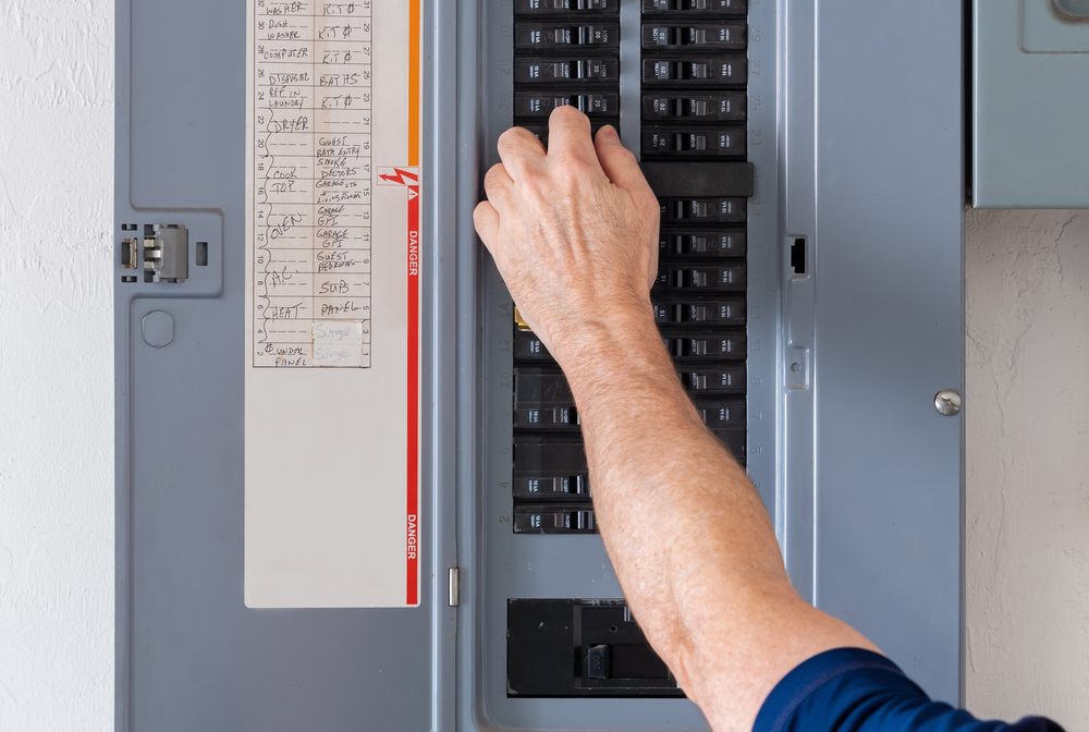 A male hand turning off power at the circuit breaker