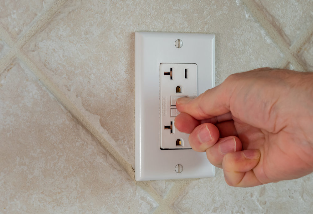 Closeup of fingers resetting a GFCI