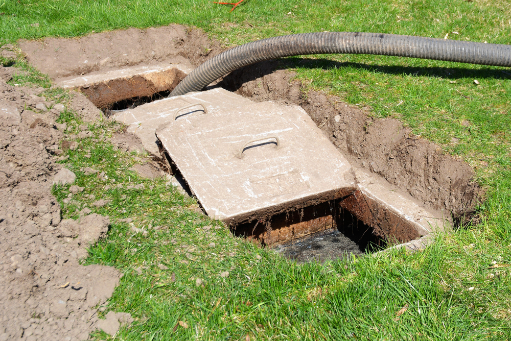 A residential septic tank with a black house inserted as it's being pumped out