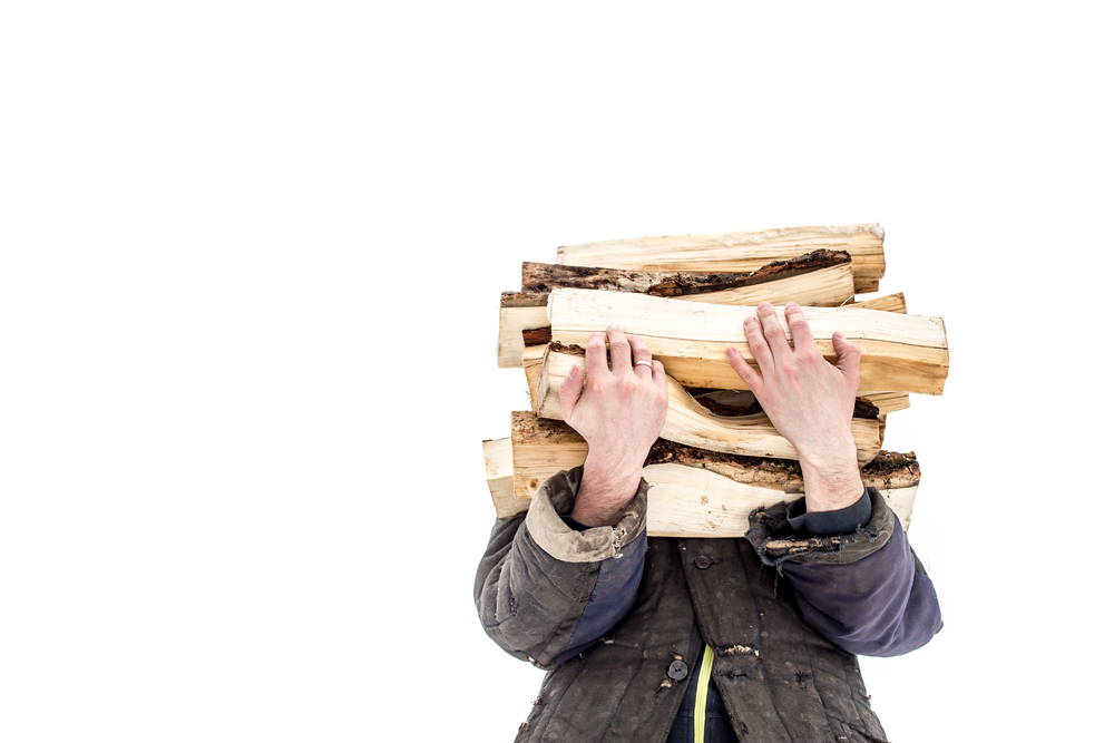 A man carrying a stack of wood, obscuring his face