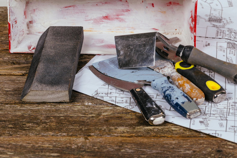 Drywall tools including trowels, a spatula, and a sanding block