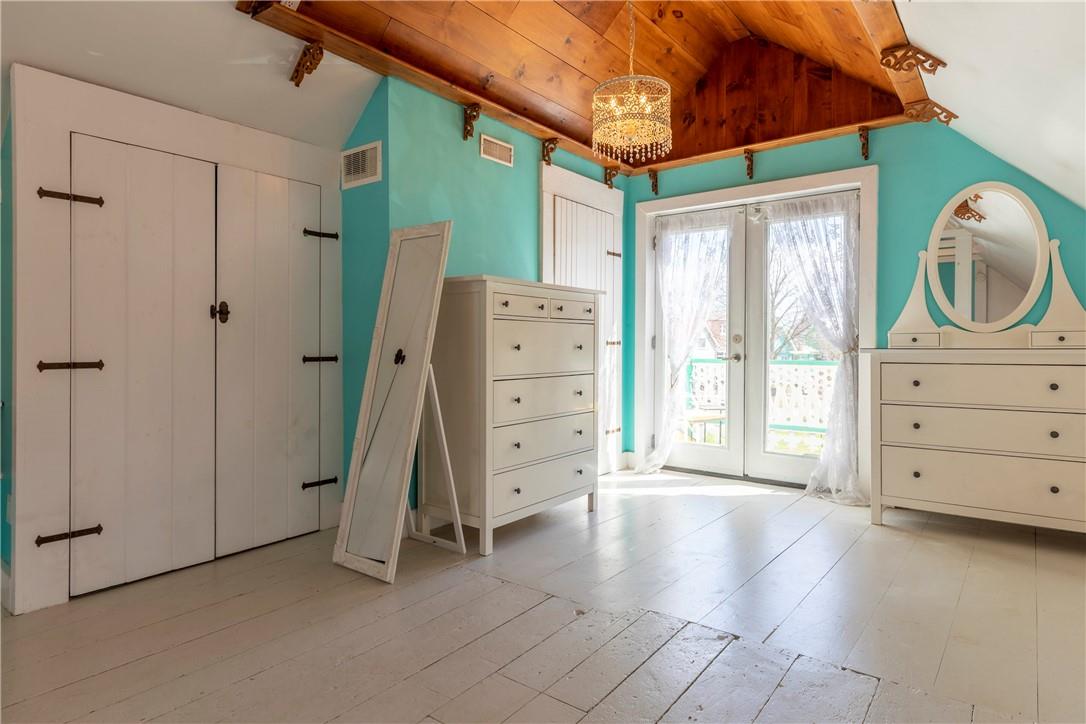 A modest room with white-washed wood flooring and light blue walls. Glass doors that open onto a balcony.