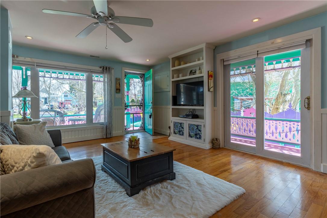 Large, open concept living room with hardwood flooring. Colours from the house exterior leak in through the bright open windows.