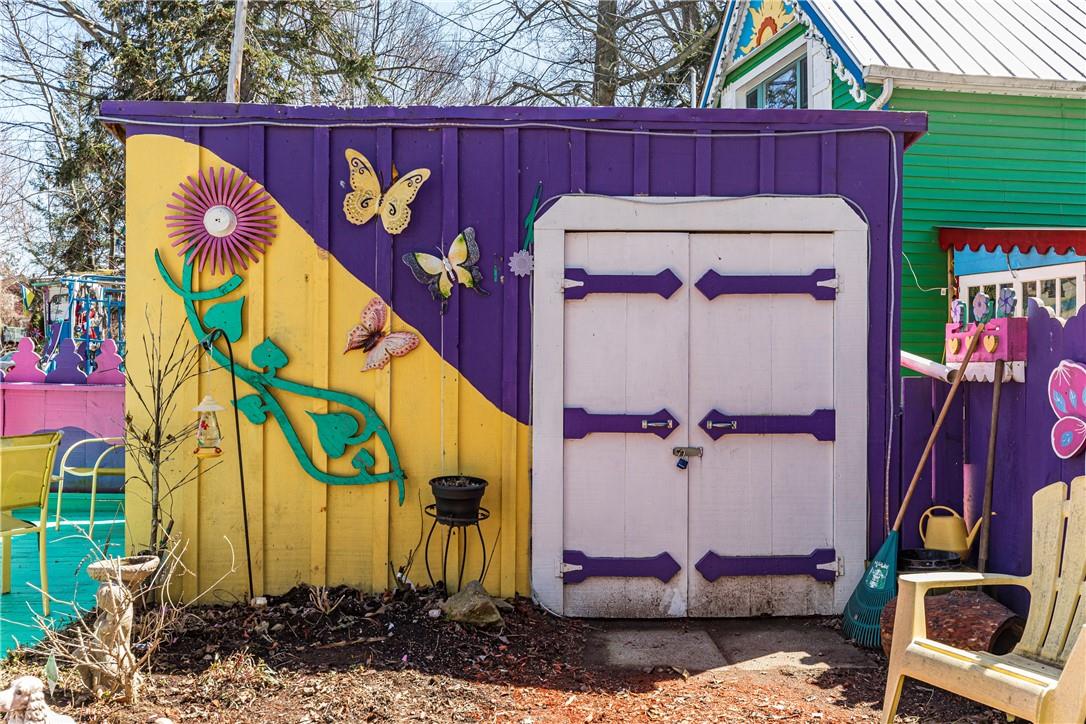 A shed painted half purple, half yellow. Decorated with yellow butterflies and a large pink flower.