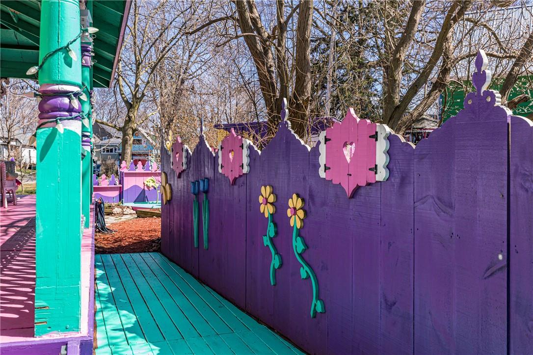 Long narrow side porch with turquoise deck and purple fencing, decorated with yellow sunflowers.