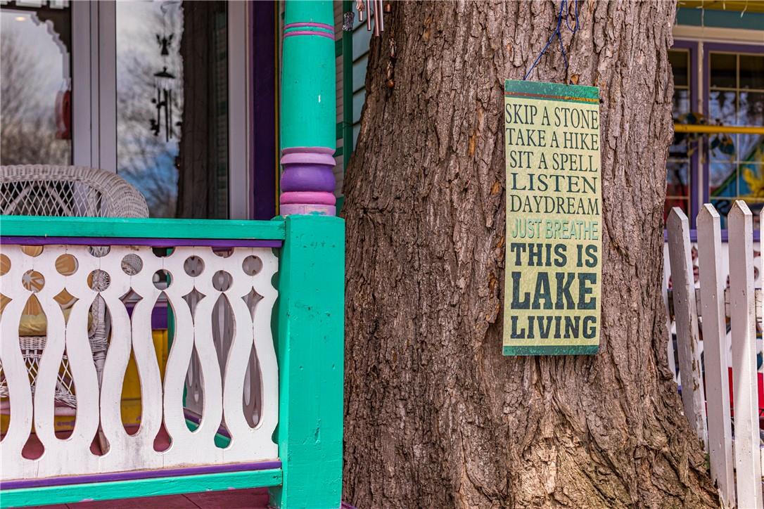 A large tree with a sign that reads, "skip a stone; take a hike; sit a spell; listen; daydream; just breathe; this is lake living."