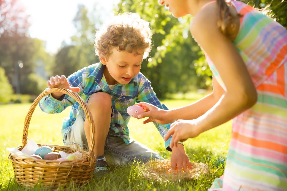 Boy and girl celebrating Easter, searching and collecting chocolate eggs.