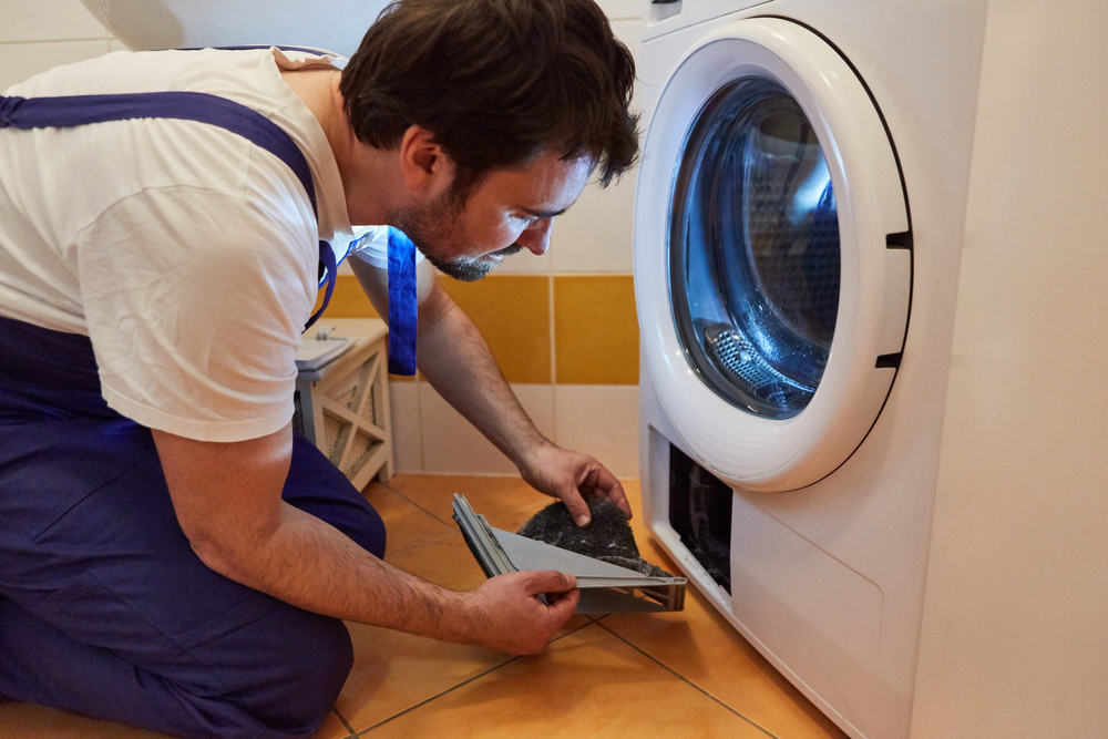 A man cleaning the lint trap from a clothes dryer