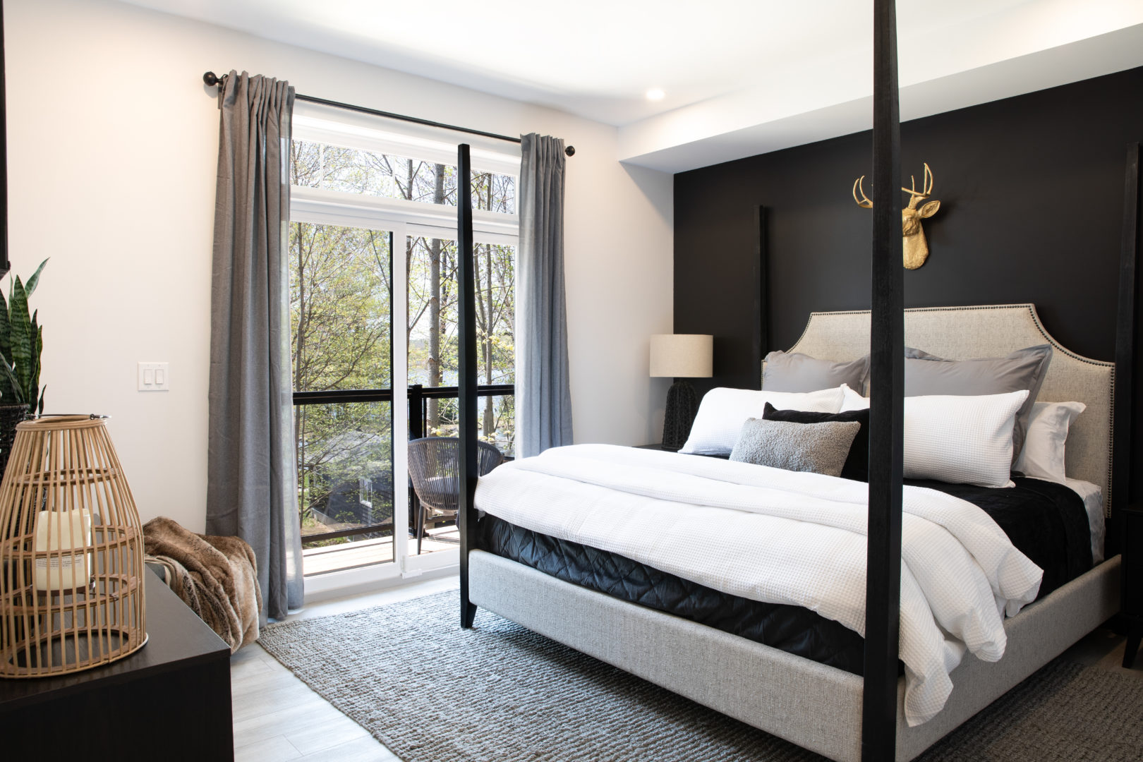 A large bedroom with a black accent wall and a door leading out to a balcony.