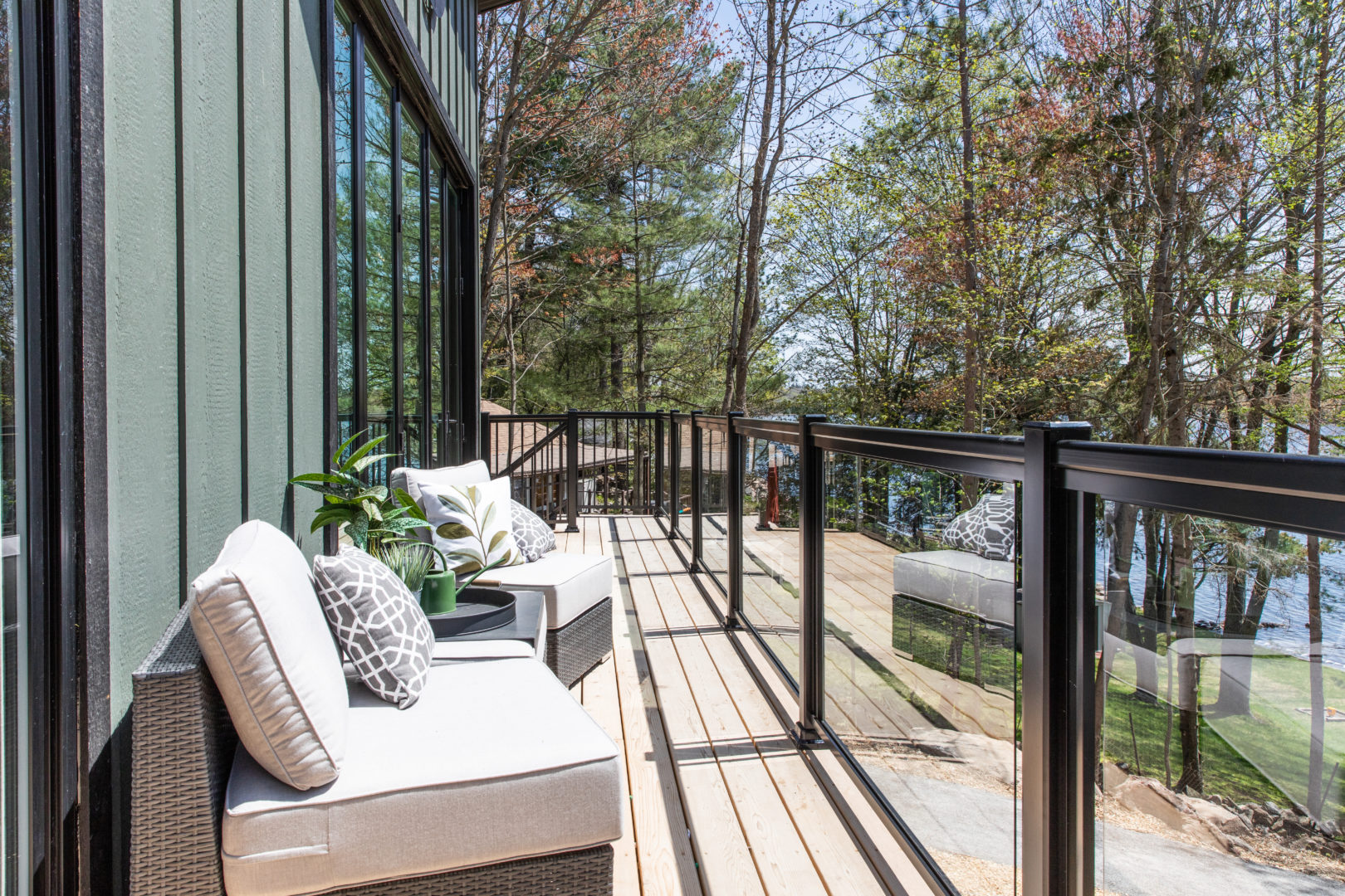 A long outdoor upper-level deck with a glass railing and seating.