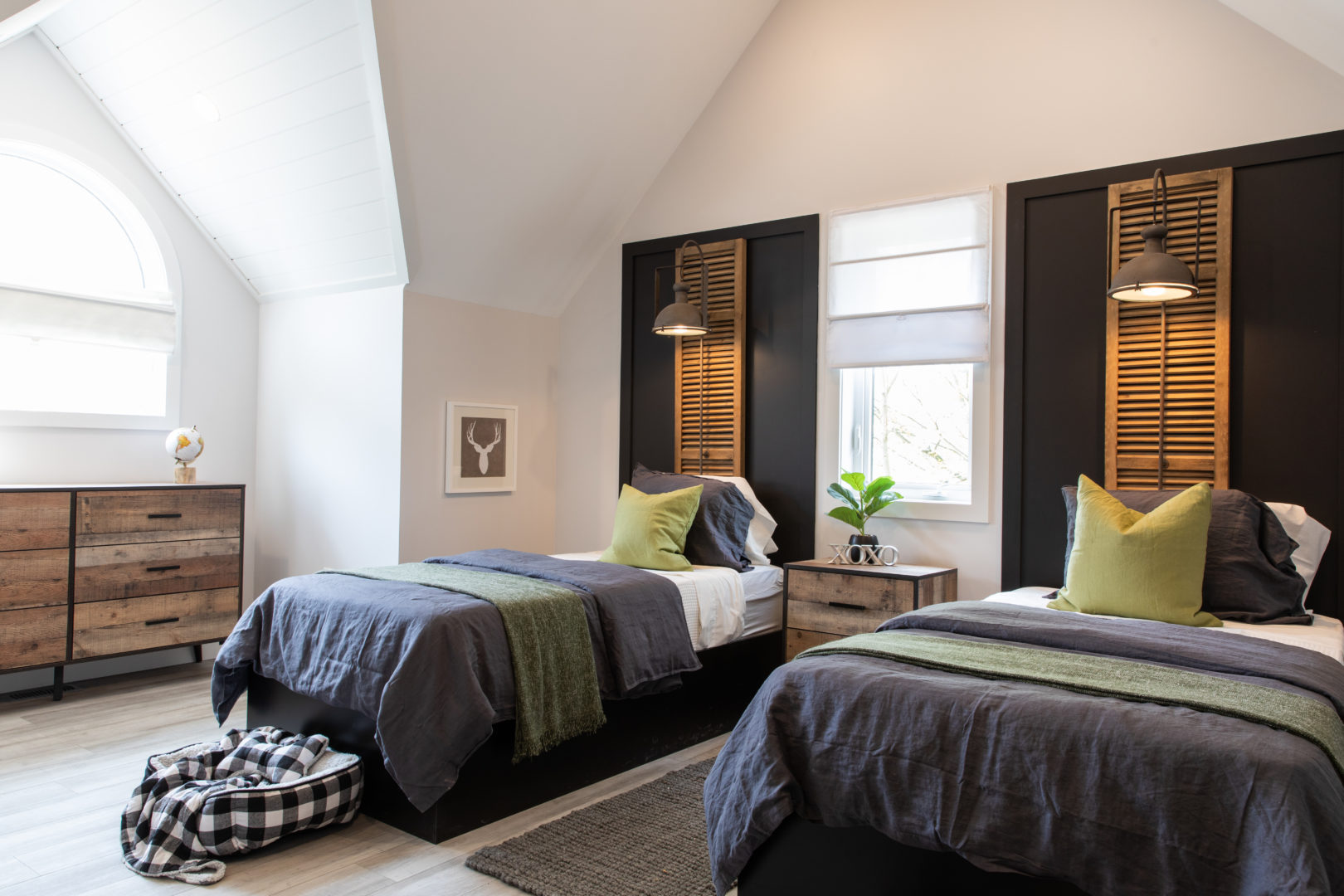 A large room with two single beds, black accent walls, and large windows.