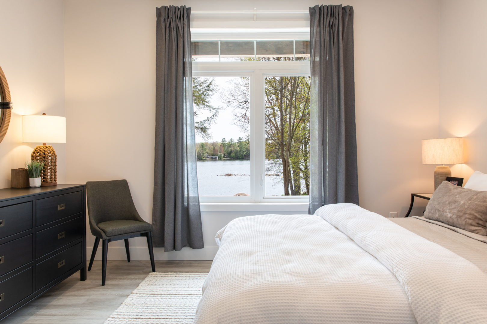 A good sized bedroom with an open window that has a view of the lake.