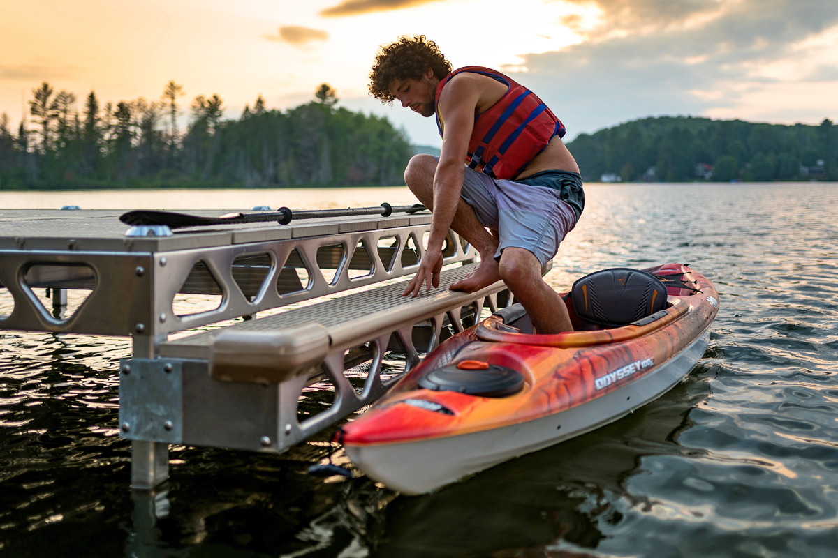 Someone climbing into a kayak attached to a kayak-friendly dock