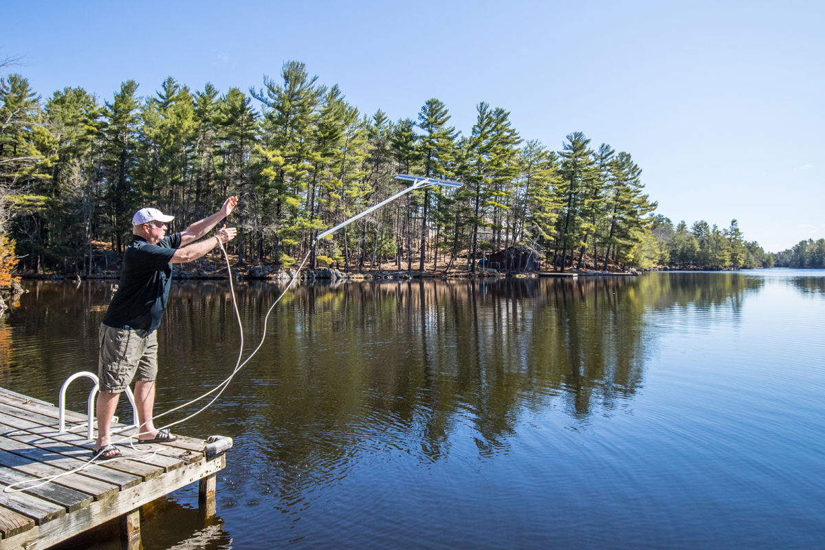 A man throwing the Jaws weed rake into the lake