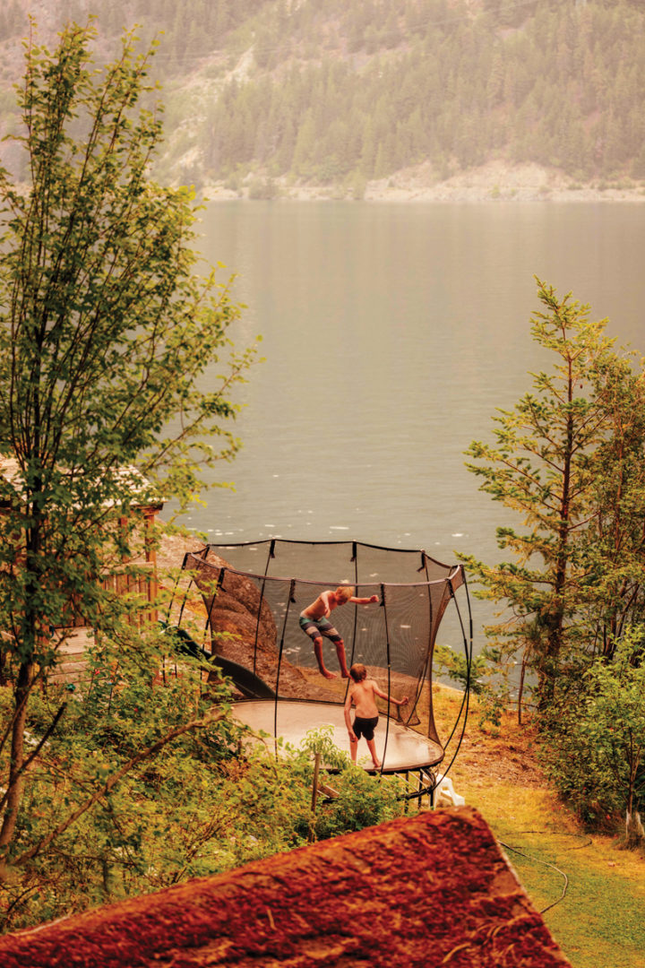 Kids play on a trampoline by the lake