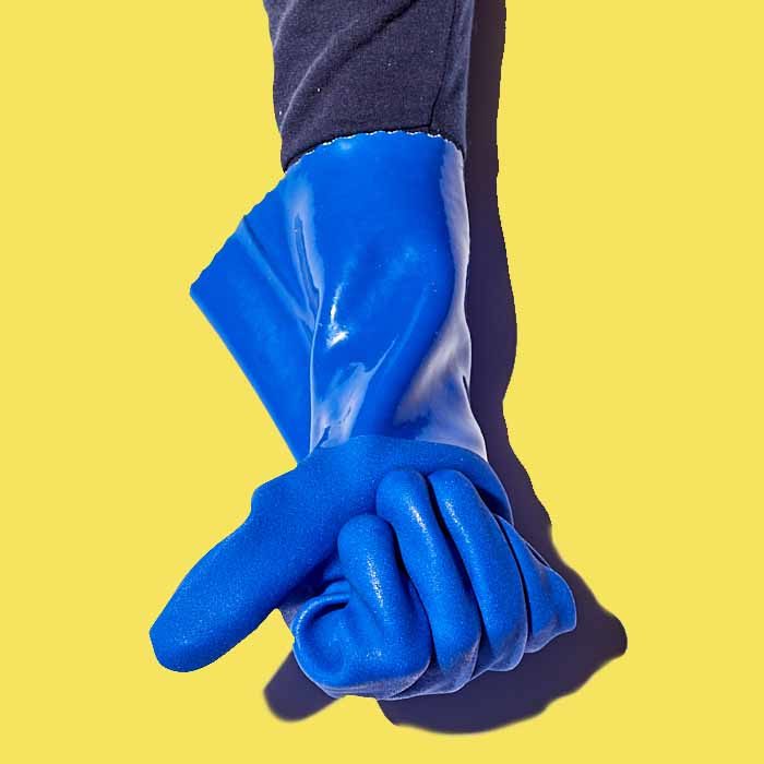 A hand wearing a cobalt blue PVC gauntlet chemical resistant glove against a yellow background.