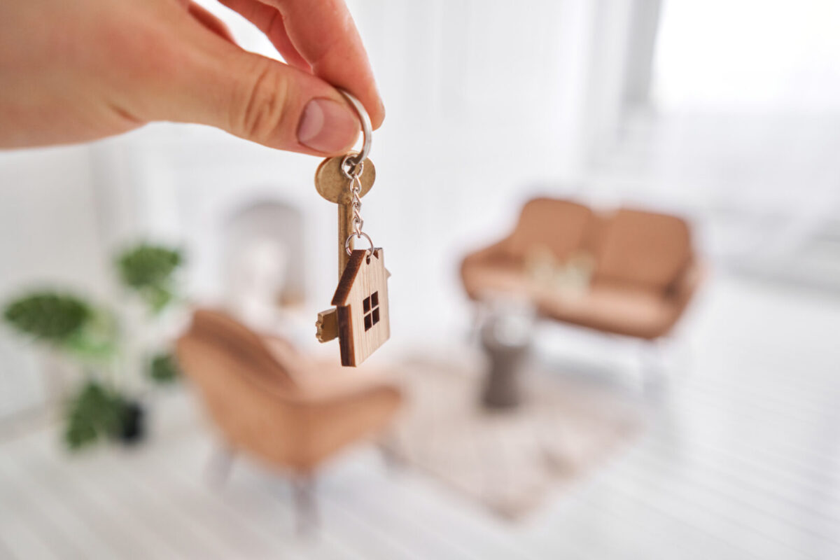 a person holding a key with a house charm
