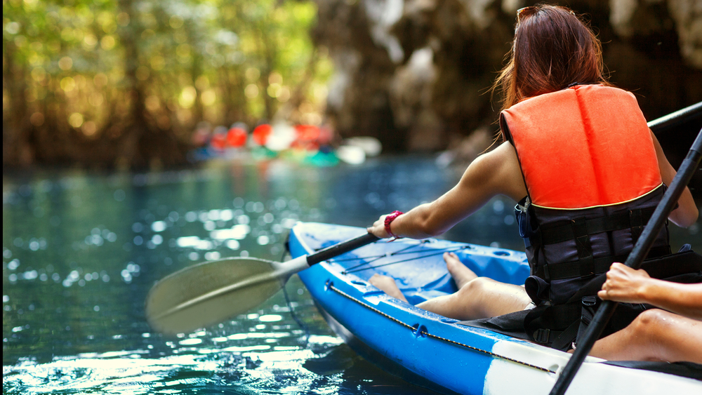 A woman paddling a tandem kayak