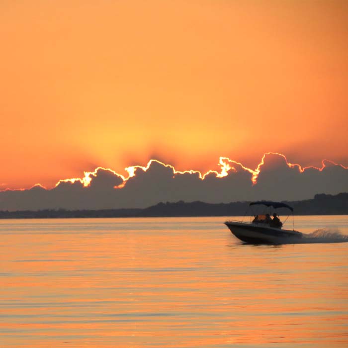 beautiful orange sunset over lake erie as a boat drives through the frame