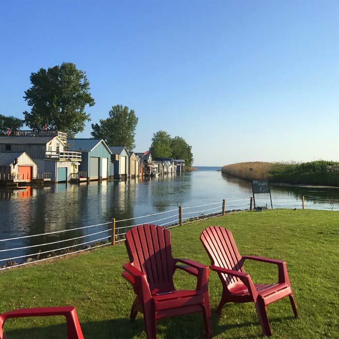 muskoka chairs overlooking a canal dotted with some houses on lake erie