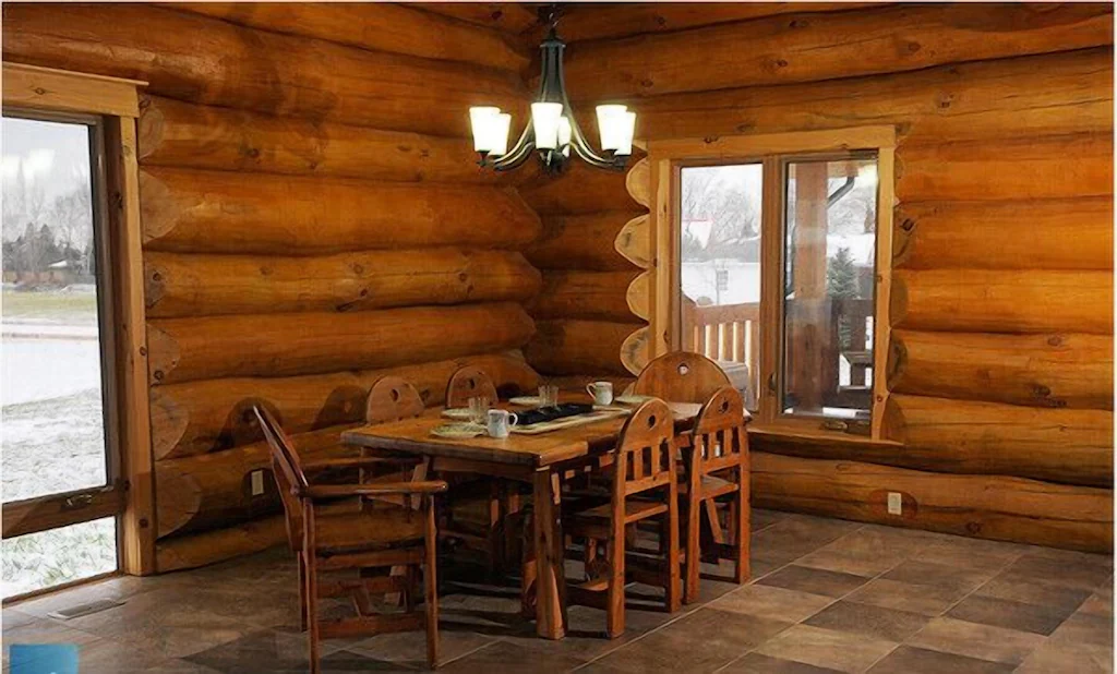 Log cottage dining room with wooden table and chairs.