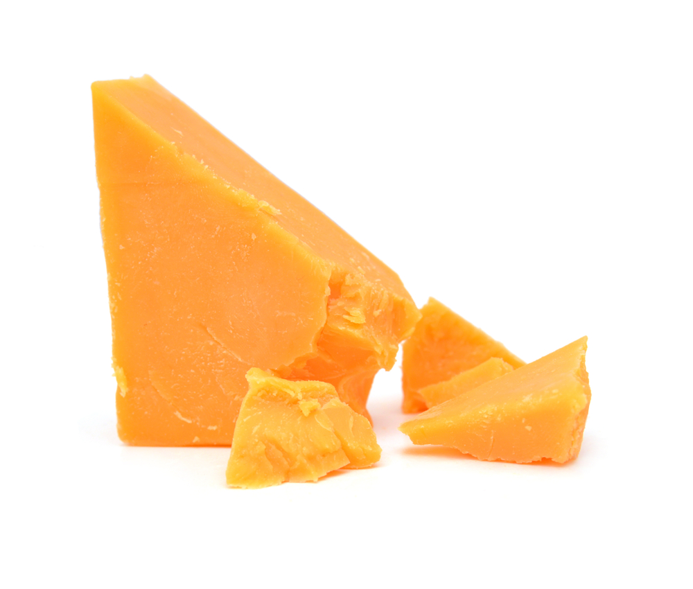 A wedge of cheddar cheese against a white background