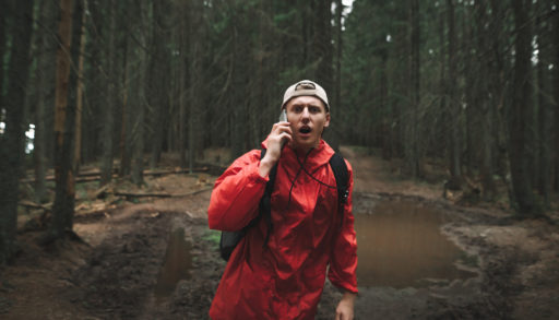 A frightened man talking on a cell phone in the woods