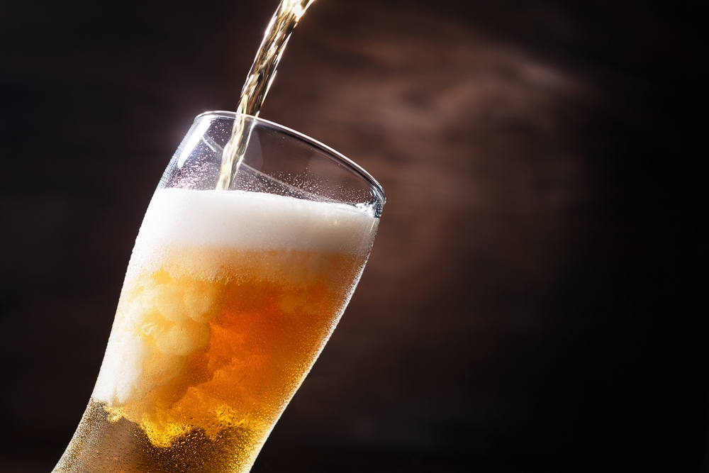 Beer pouring into a glass against a dusky black background