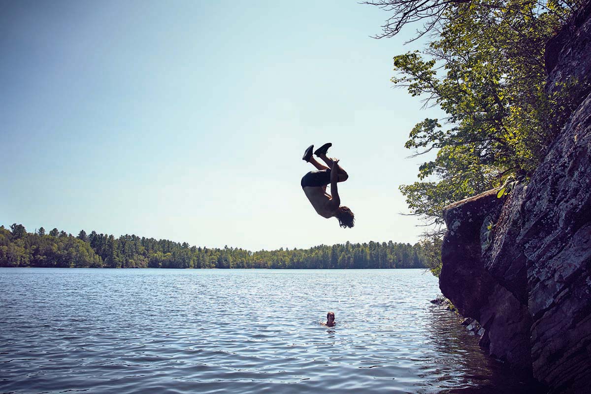 Simon does a flip into a lake.