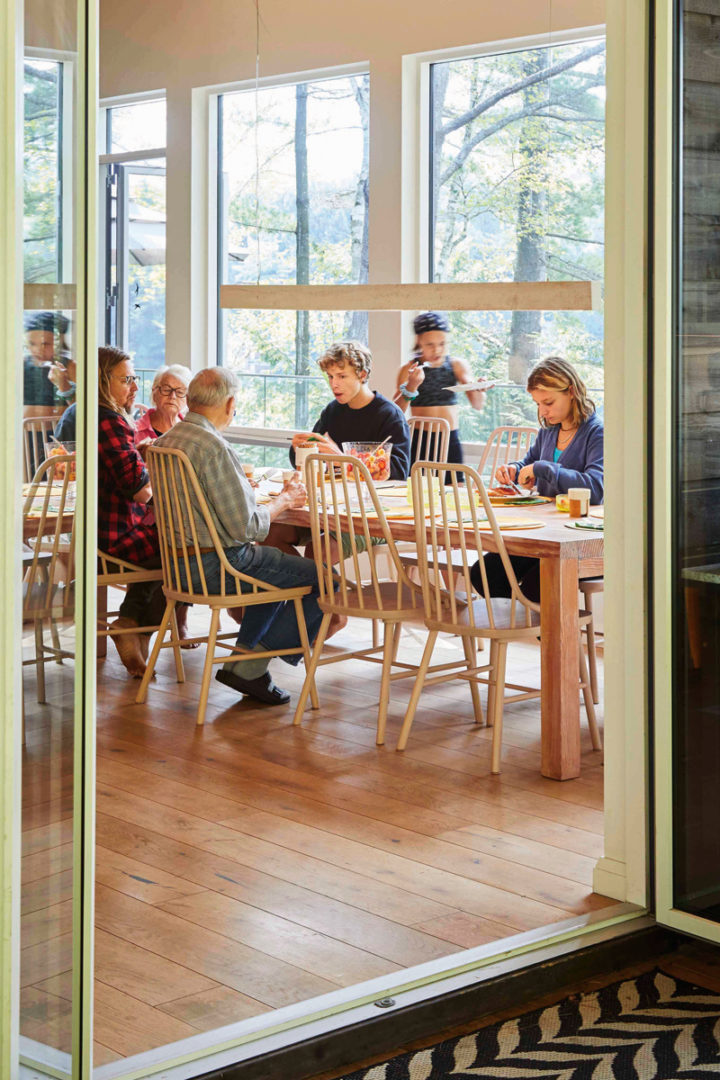 the family sits at the big dining room table, as seen from outside