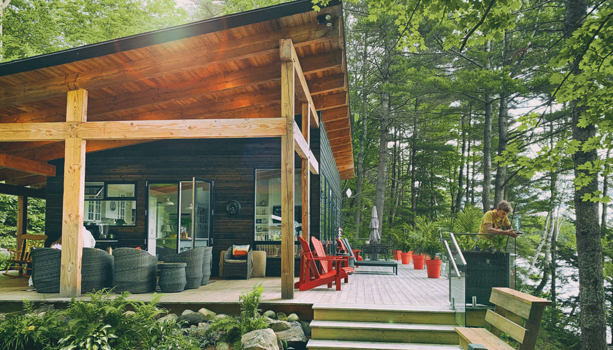 the exterior of the Kelars newly built cottage with a wrapround porch and the sun shining
