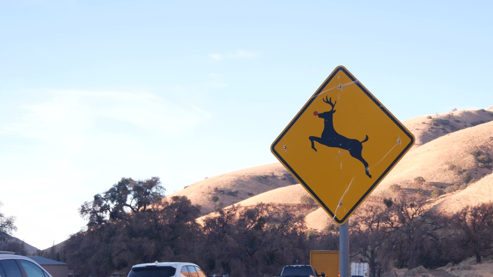 A deer crossing sign on a busy road