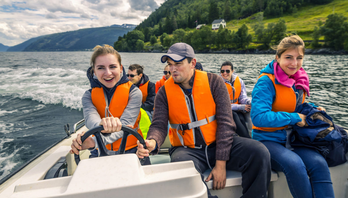 Portrait of young and attractive people, friends in the motorboat driving somewhere on a picnic. Happy faces, having fun, Norway.