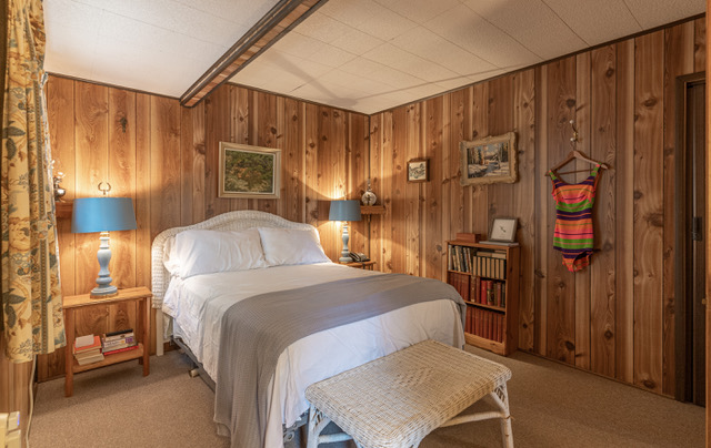 interior of a bedroom with wood panelling with a queen sized bed