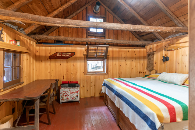 interior of a bedroom with wood on the walls with a king-sized bed