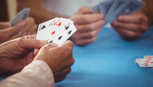 Several sets of hands holding playing cards as a group plays a card game