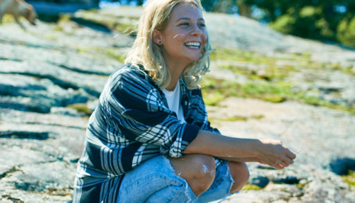 lauren patchett sits on a rock on Georgian bay looking out at the lake near her store The Hive