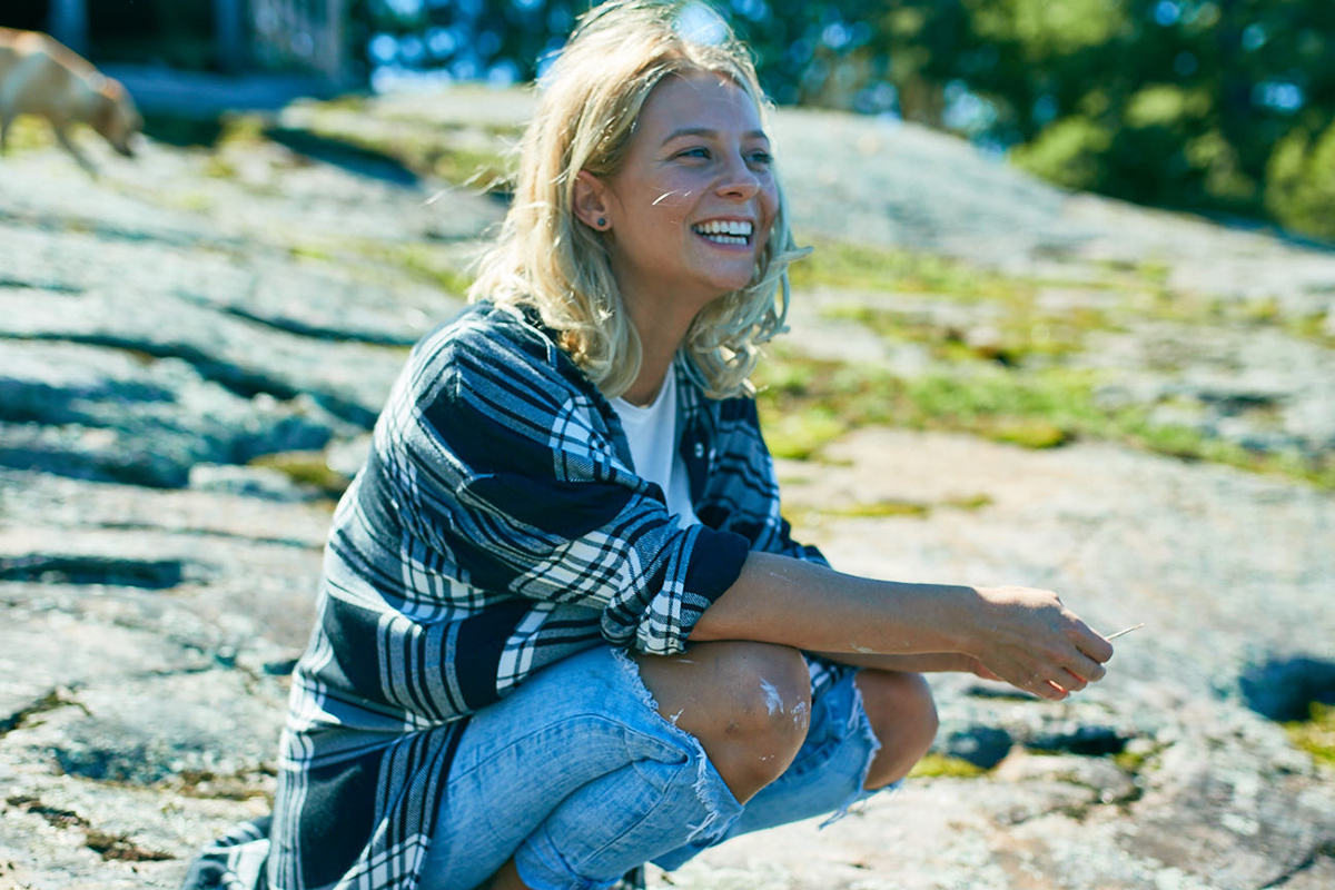 lauren patchett sits on a rock on Georgian bay looking out at the lake near her store The Hive