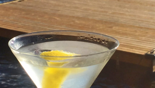martini with a twist in a glass with a dock and a lake in the background