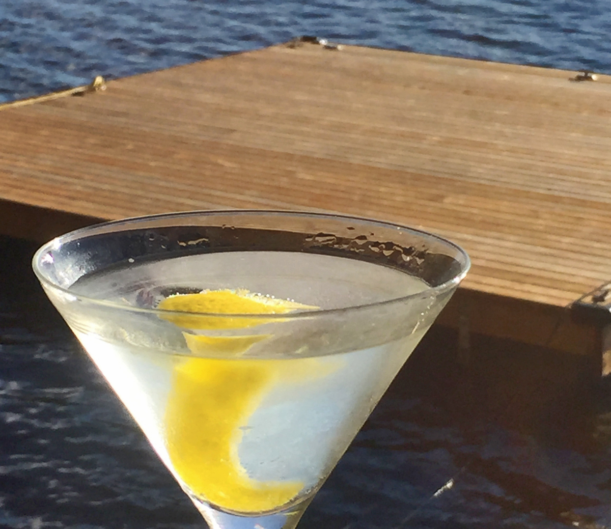 martini with a twist in a glass with a dock and a lake in the background