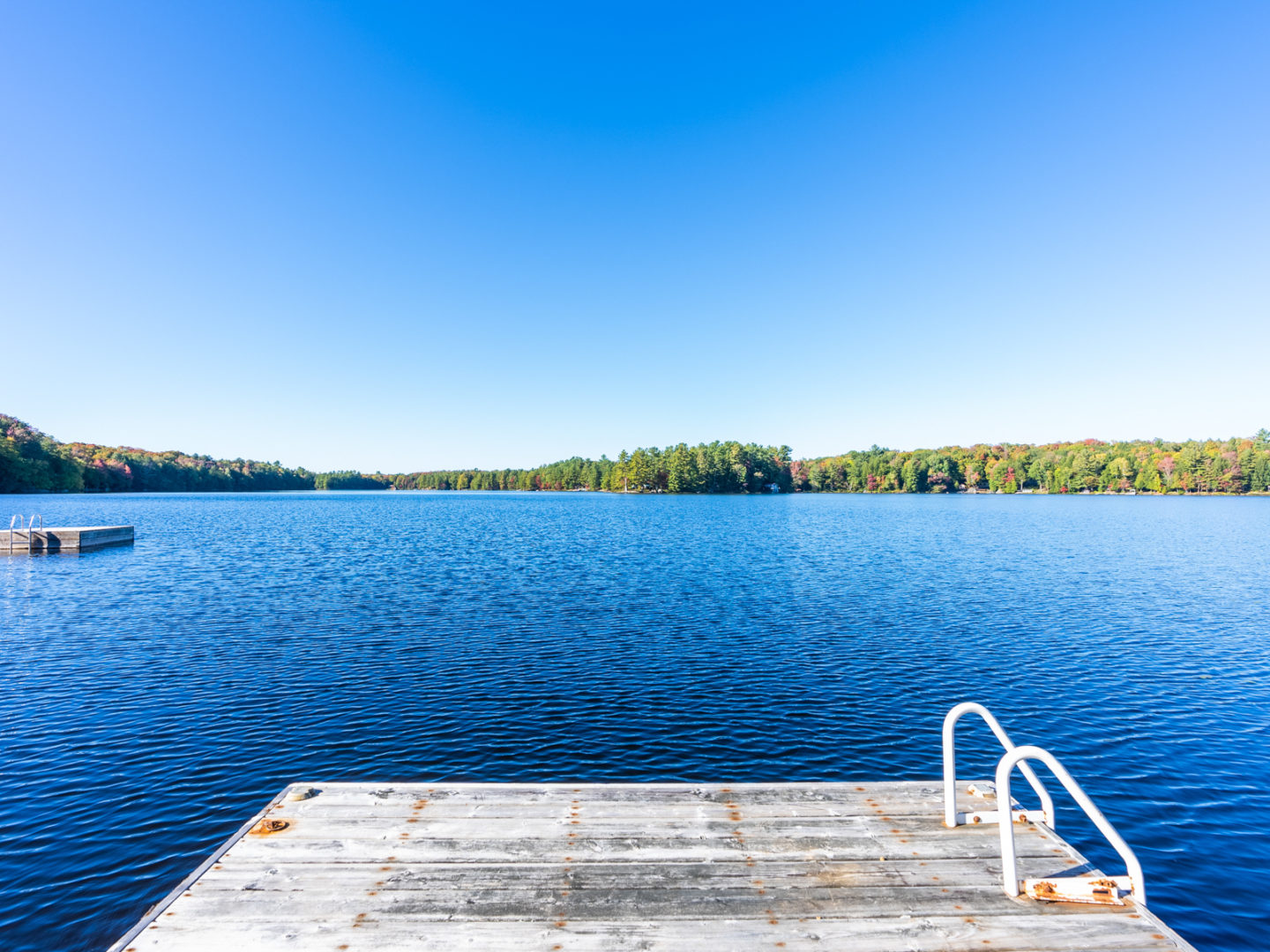 The end of a dock, looking out to a wide blue lake.
